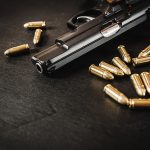 69659948-negro-pistola-y-cartuchos-en-una-mesa-de-madera-negro